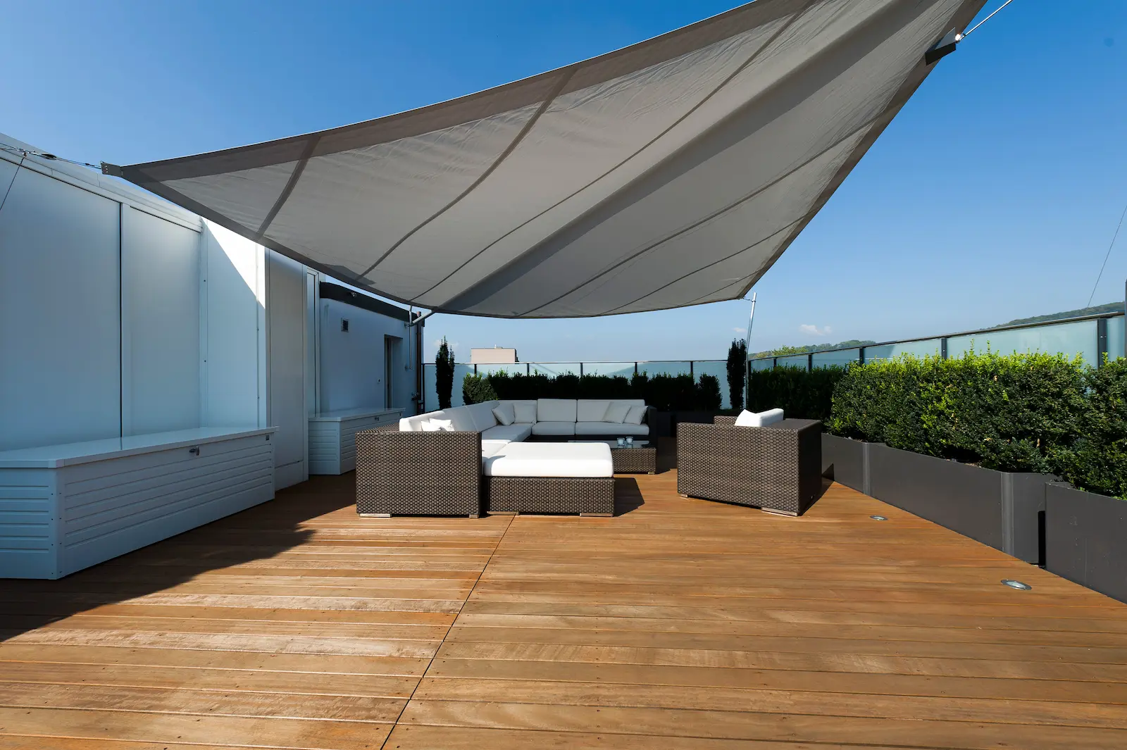 Terrasse eines Mehrfamilienhauses in Kleindöttingen mit neuem Terrassenboden aus Sipo-Holz, Sonnensegel und Loungemöbeln