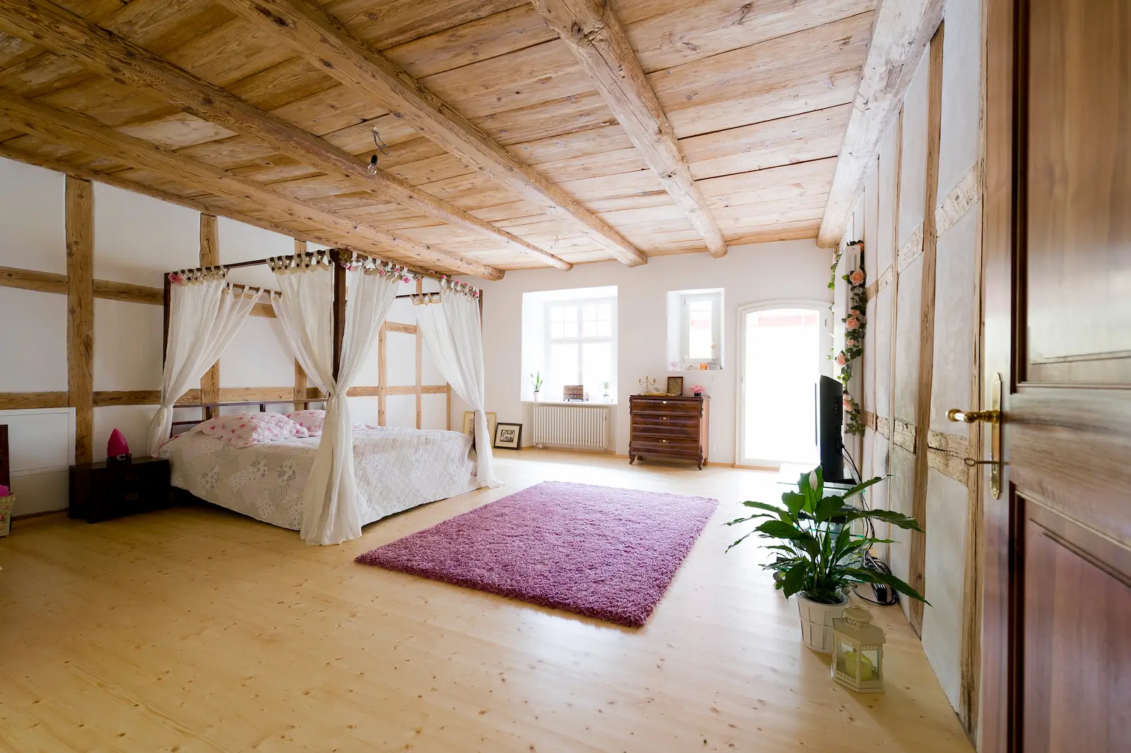 Historisches Schlafzimmer im Schloss Hilfikon mit restauriertem Holzboden und sichtbarer Balkendecke
