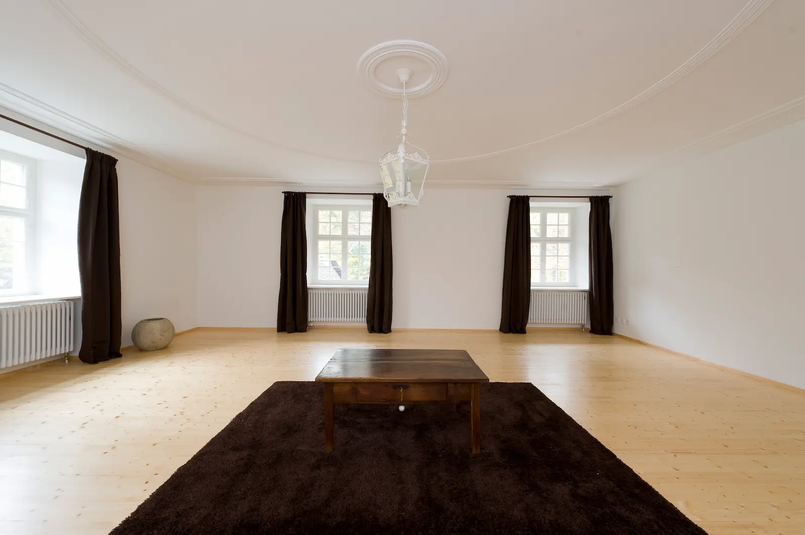 Sanierter Holzboden aus Massivholz im Saal des Schlosses Hilfikon mit Sitzbank und sichtbarer Dachkonstruktion