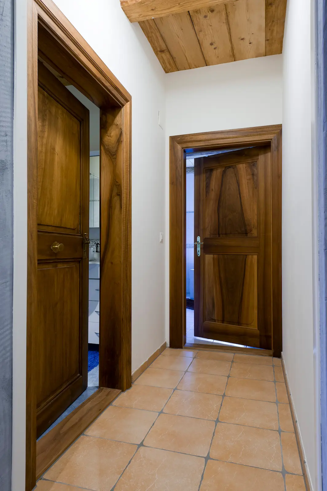 Restaurierte Holztüren im Schloss Hilfikon in einem Korridor mit Tonplattenboden und Holzbalkendecke