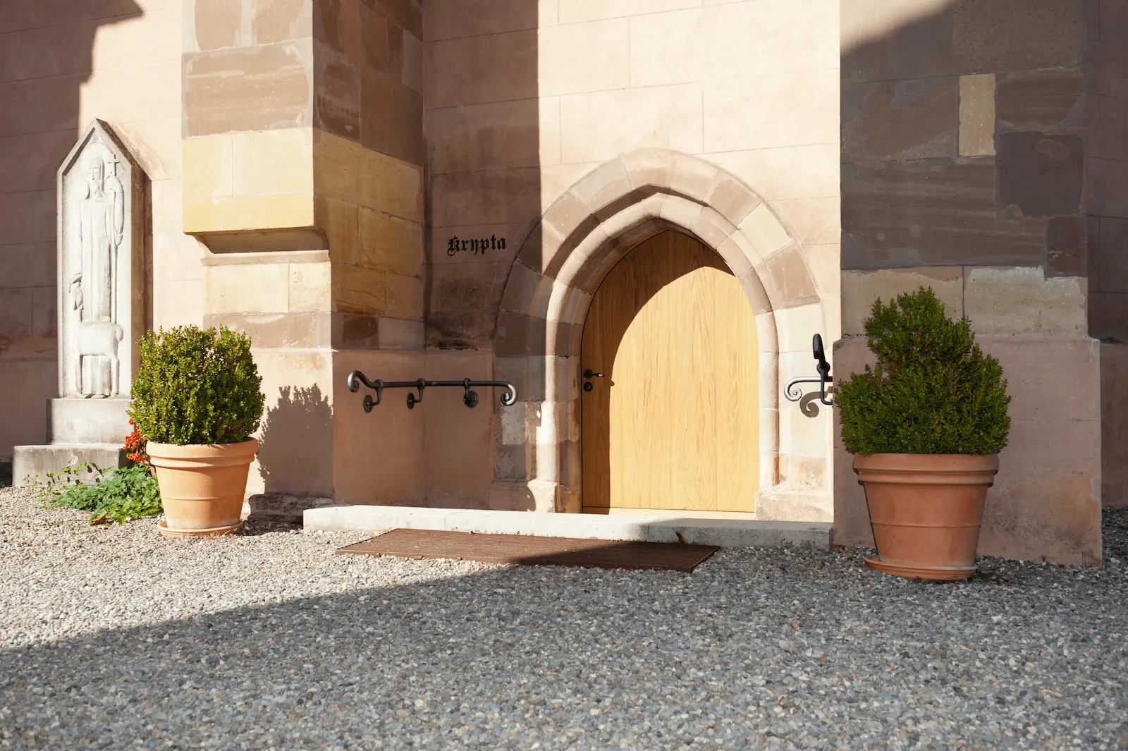 Aussenansicht der neu eingebauten Massivholz-Türe aus Eiche im Verenamünster Bad Zurzach, mit gotischem Rundbogen und steinerner Fassade.