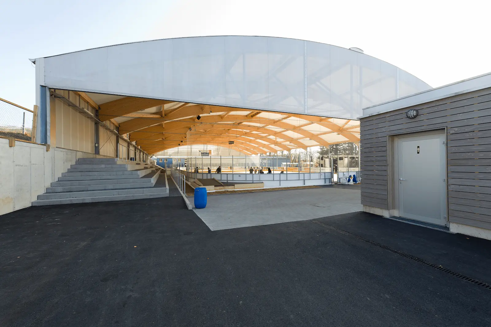 Überdachung der Eisbahn Urdorf mit sichtbarem Holztragwerk und Zuschauertribüne