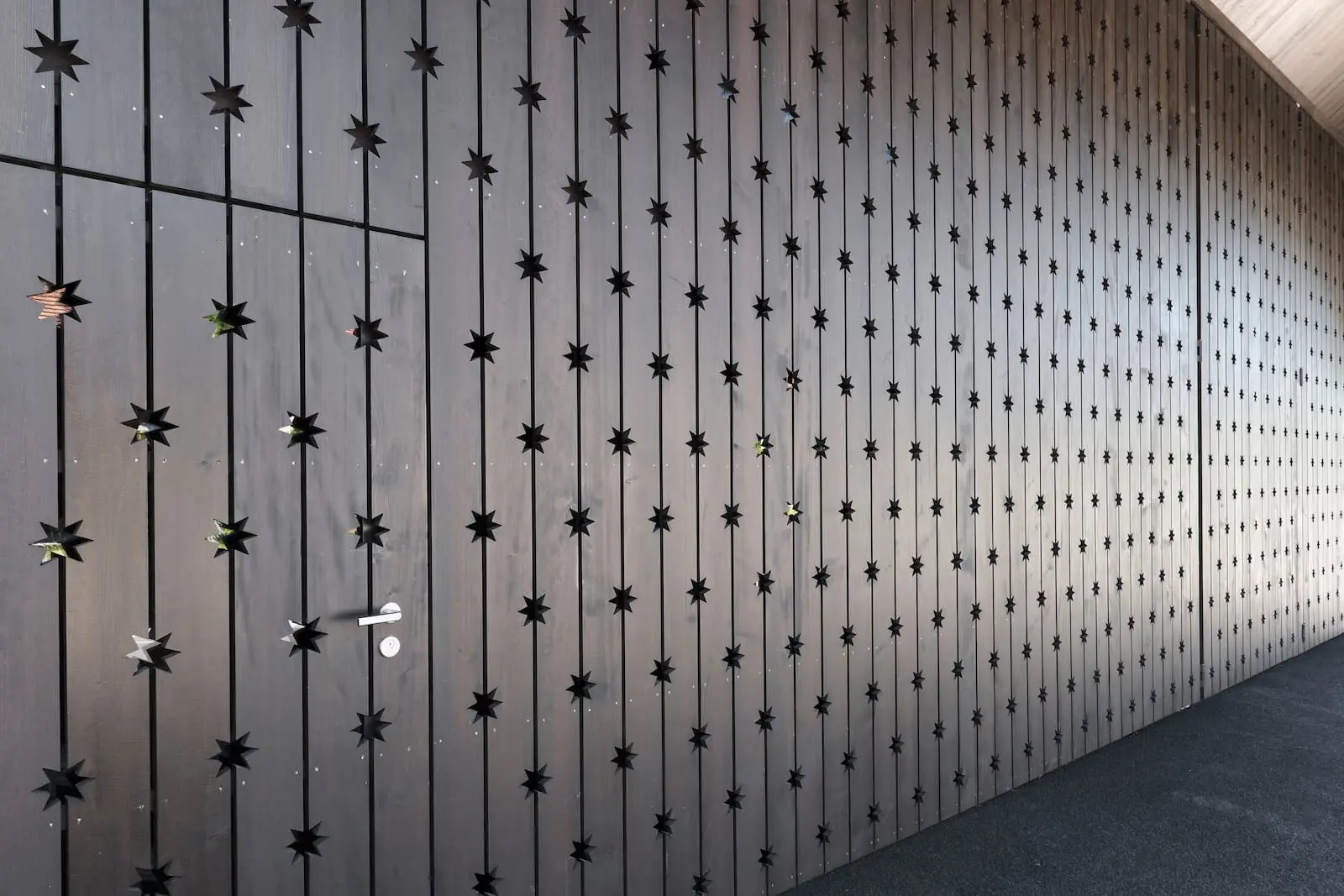 Detail der sternförmigen Gravuren in der dunklen Holzfassade des Weinguts Würenlingen