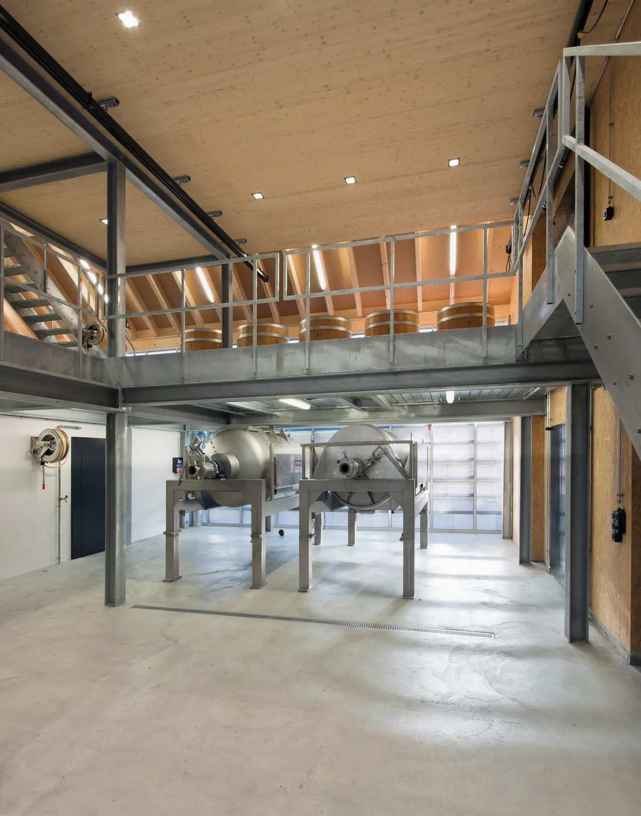 Innenansicht des Dachtragwerks im Weingut Würenlingen mit Holzträgern und Stahlbühne