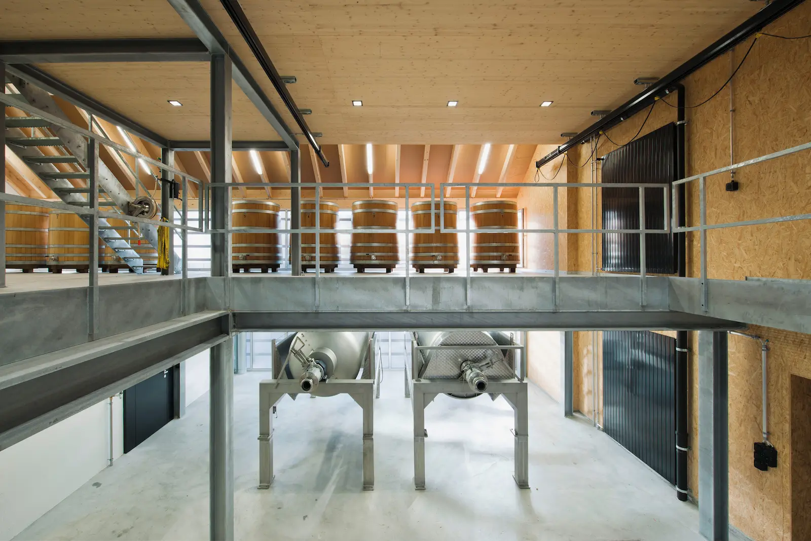 Tragwerk des Dachstuhls mit sichtbaren Holzträgern über dem Gärraum des Weinguts Würenlingen