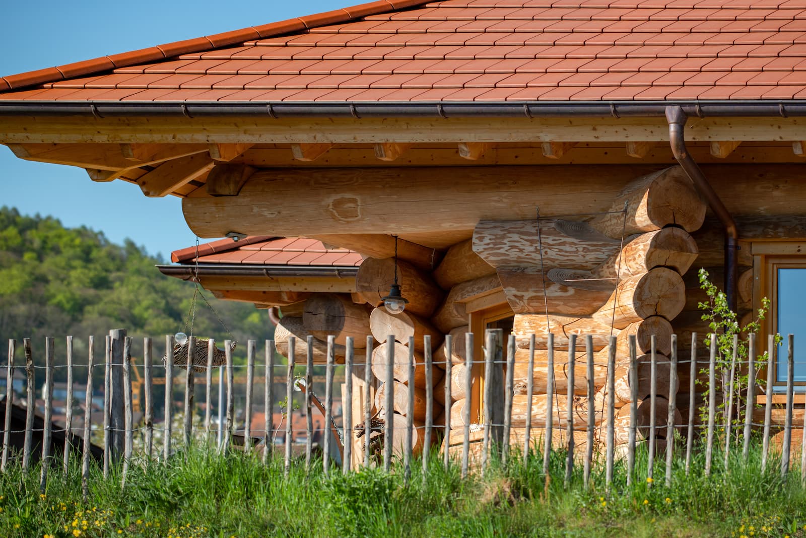 Blockhauswand aus Rundholz mit Fenster und Dachanschluss.