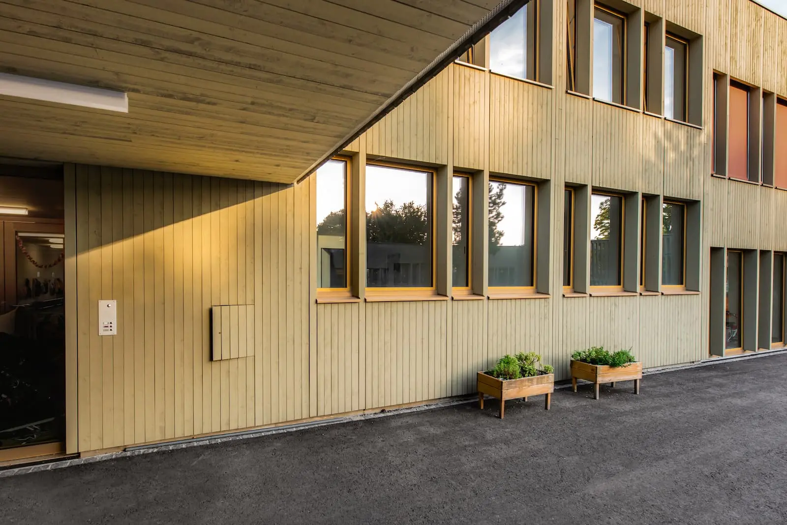 Seitenansicht des Chinderhuus Goldiland mit Holzfassade und Fensterelementen im Massivbauabschluss