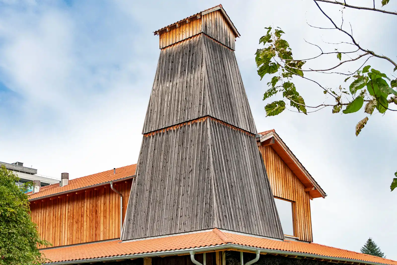Aussenansicht der Biosauna mit Turm in Holzelementbauweise, Fassade aus Lärche und Ziegeldach.