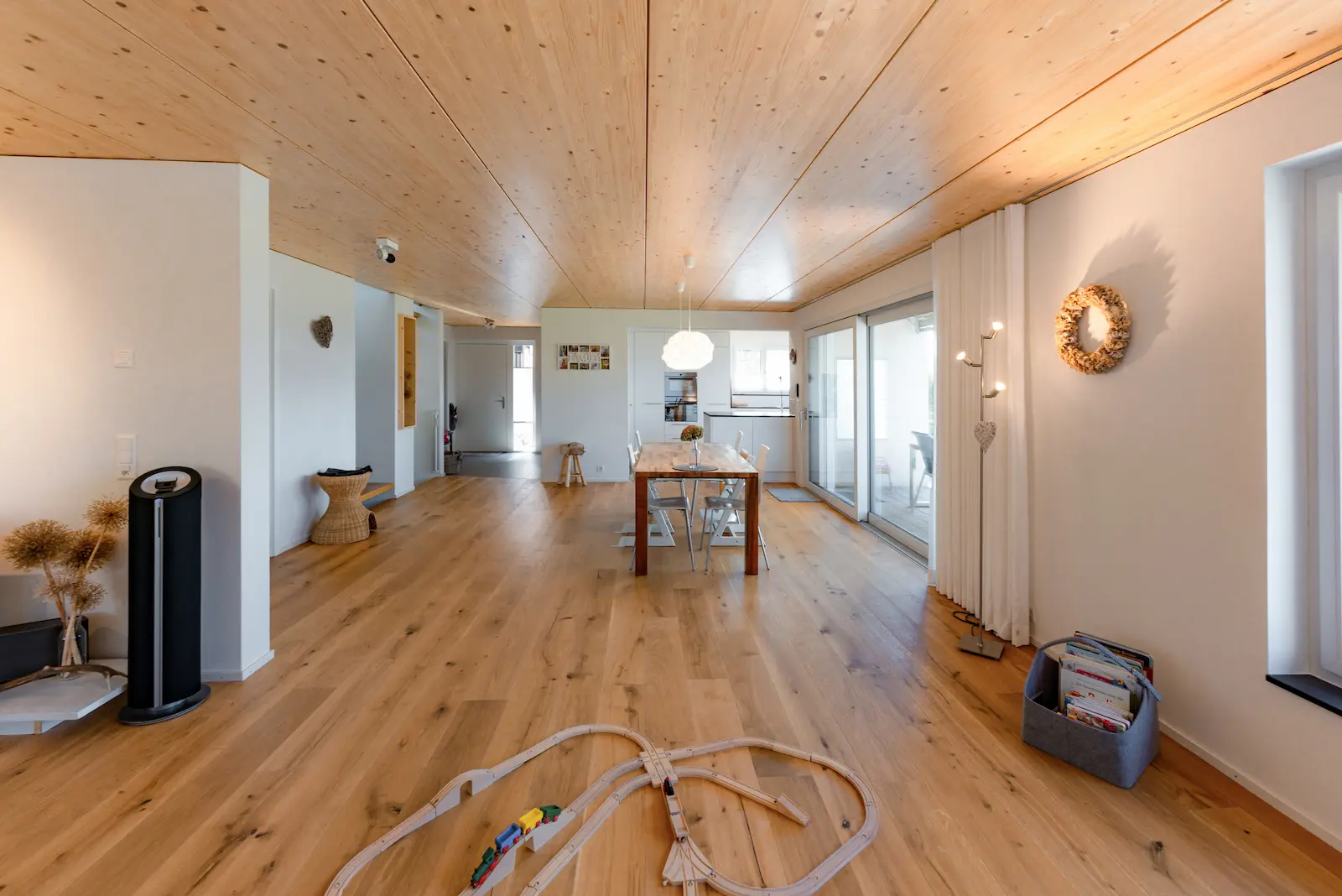 Grosszügiger Wohnraum mit durchgängigem Massivholzboden, natürlicher Holzdecke und viel Tageslicht im Einfamilienhaus in Holzelementbauweise.