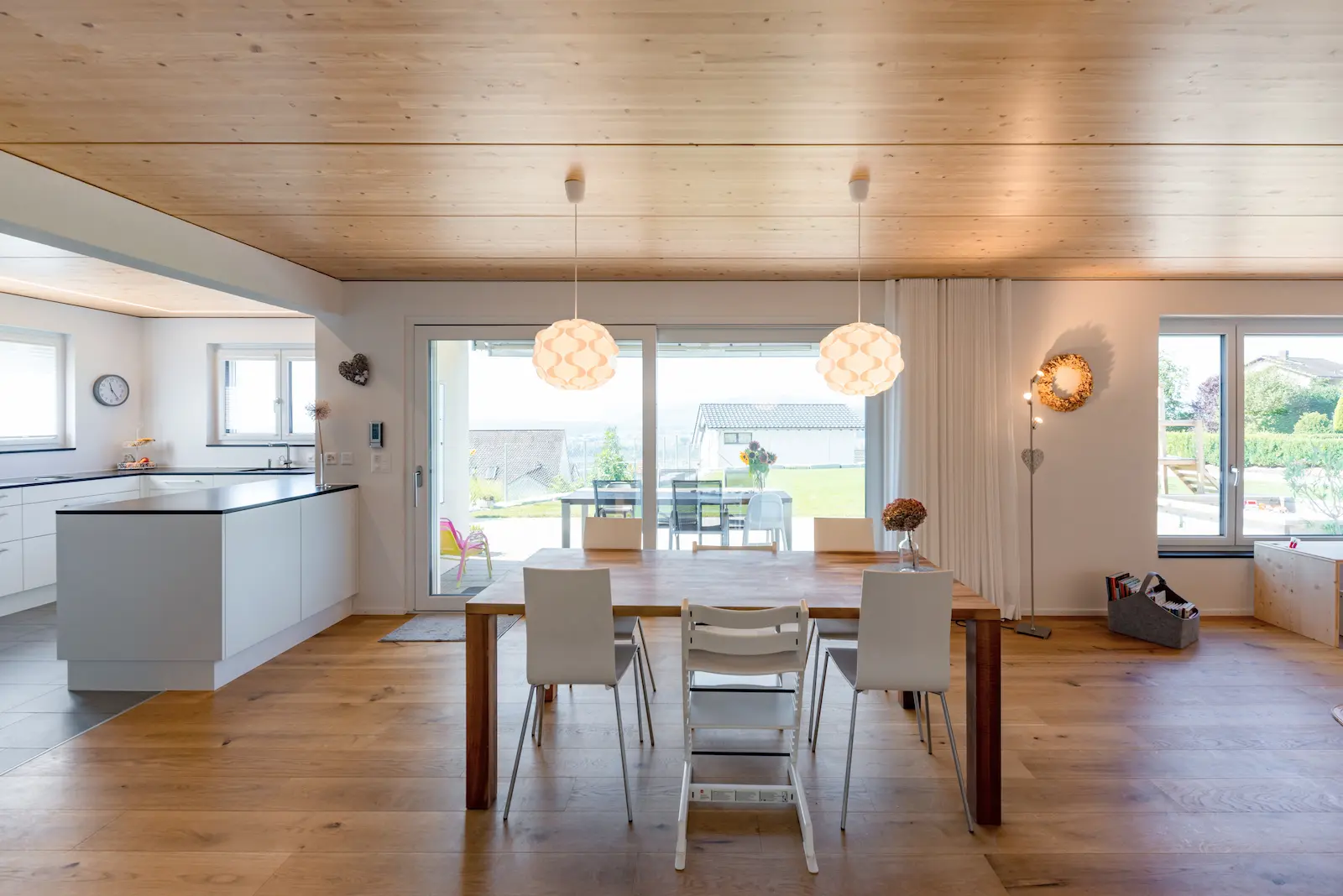 Offener Wohn- und Essbereich mit Massivholzboden und Holzdecke im Einfamilienhaus Klingnau, lichtdurchflutet dank grossen Fenstern und Schiebetür.