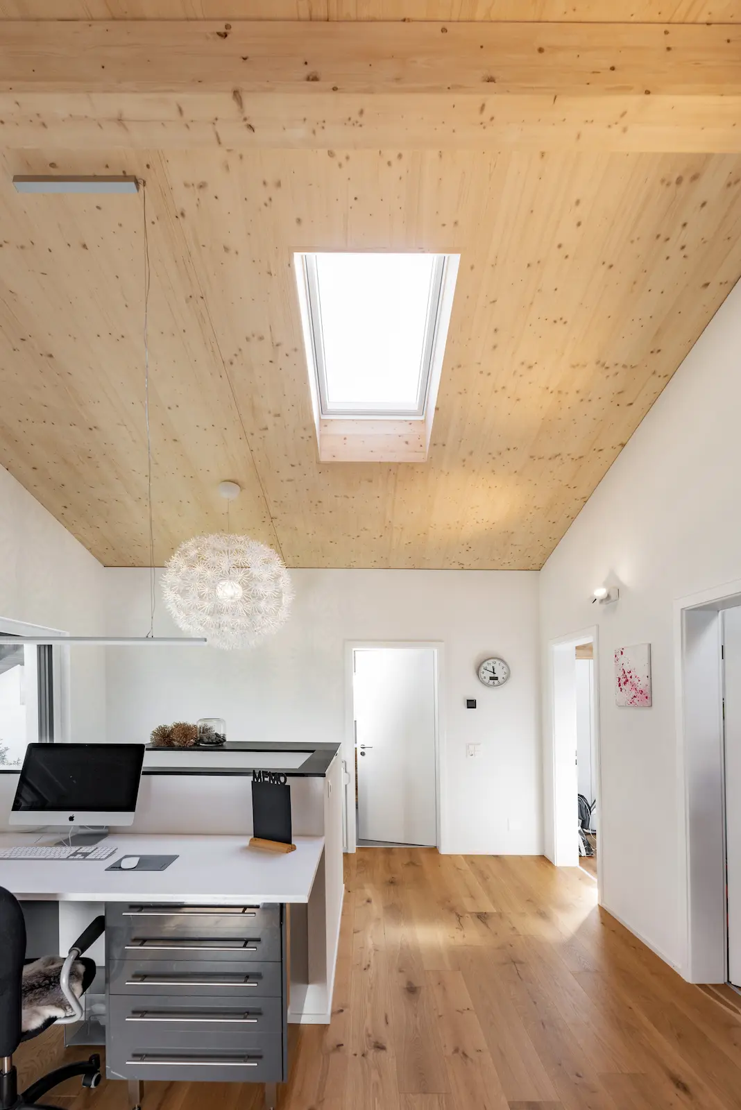 Velux-Dachfenster mit Aussenrollladen für sommerlichen Wärmeschutz in Kombination mit sichtbarer Holzdecke im Dachgeschoss eines Holzbaus.