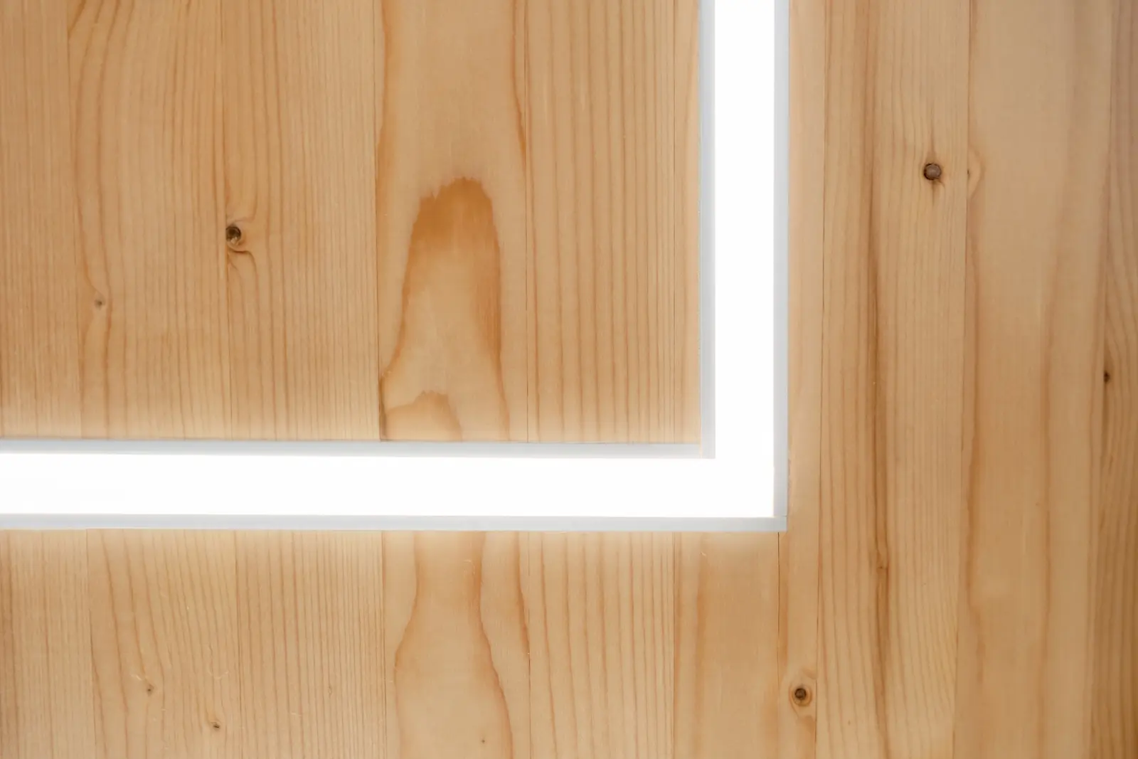 Präzise gearbeitete Massivholzverkleidung mit integrierter LED-Lichtleiste – modernes Detail im hochwertigen Innenausbau aus Holz.