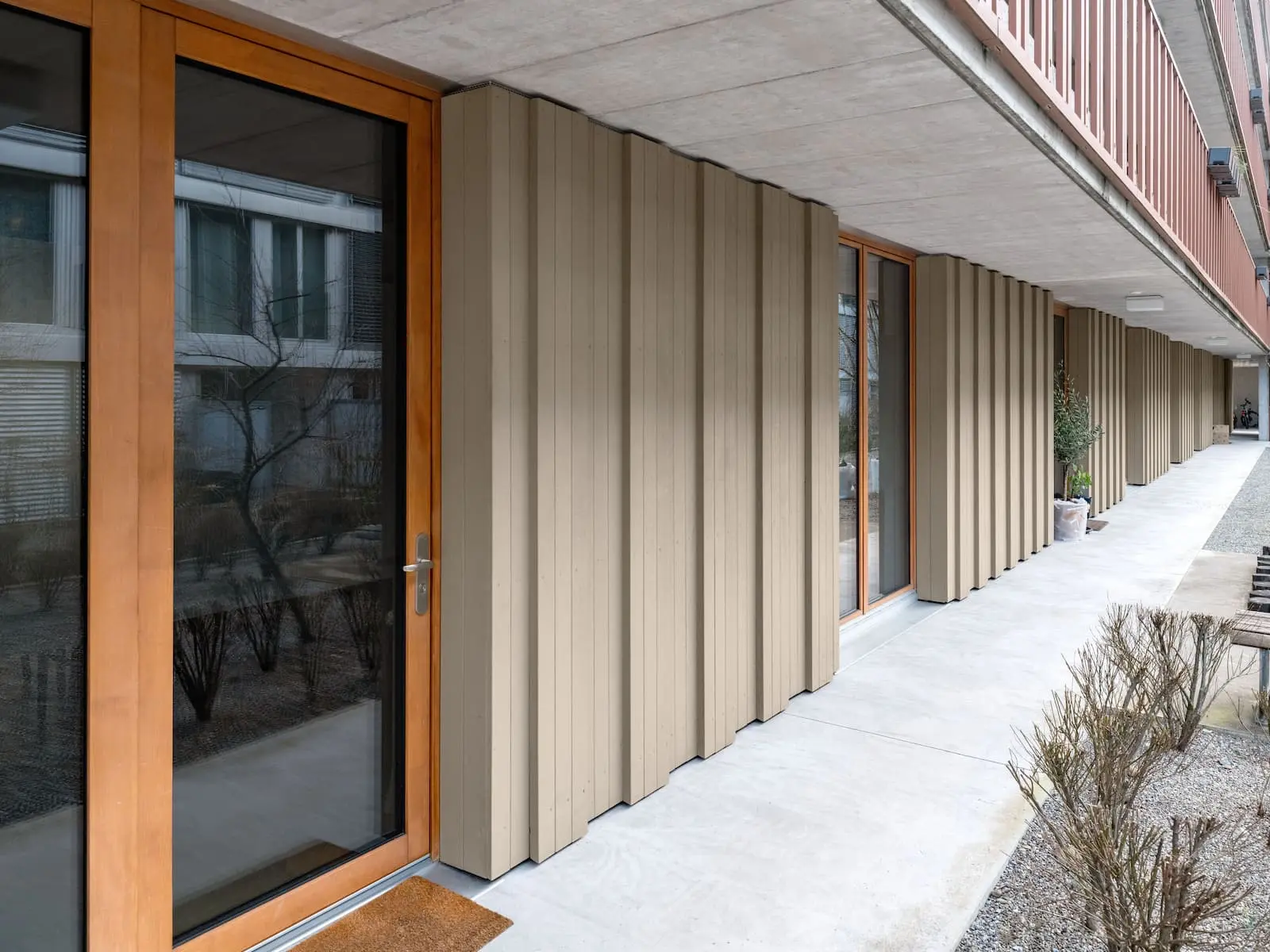 Holzfassade mit zurückversetzten Hauseingängen – wetterfest beschichtet für dauerhafte Qualität und schlichte Gestaltung.