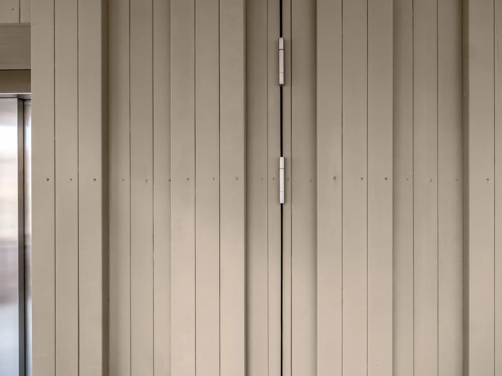 Detail der Holzfassade mit integrierter Tür und sichtbaren Beschlägen – präzise Ausführung in Schweizer Holz.