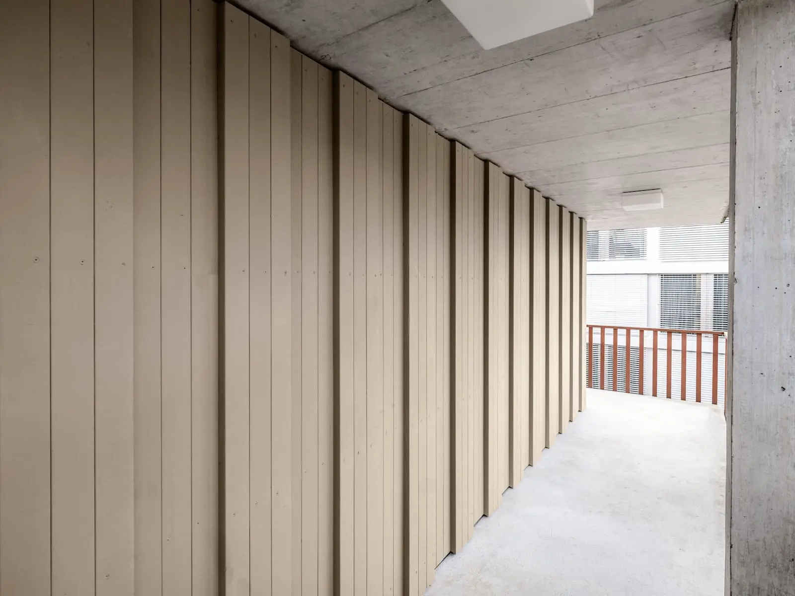 Vertikal strukturierte Holzfassade im überdachten Aussenbereich des Mehrfamilienhauses an der Gartenstrasse in Baden.