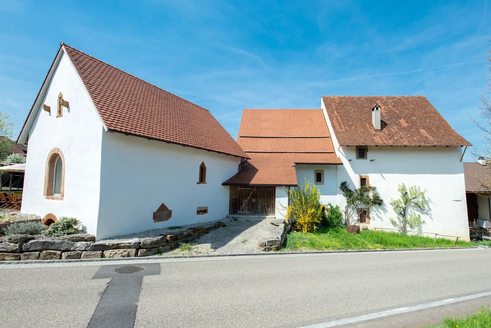 Gesamtansicht der sanierten Gebäudeanlage in Hottwil mit weissen Fassaden und neu eingedecktem Ziegeldach.