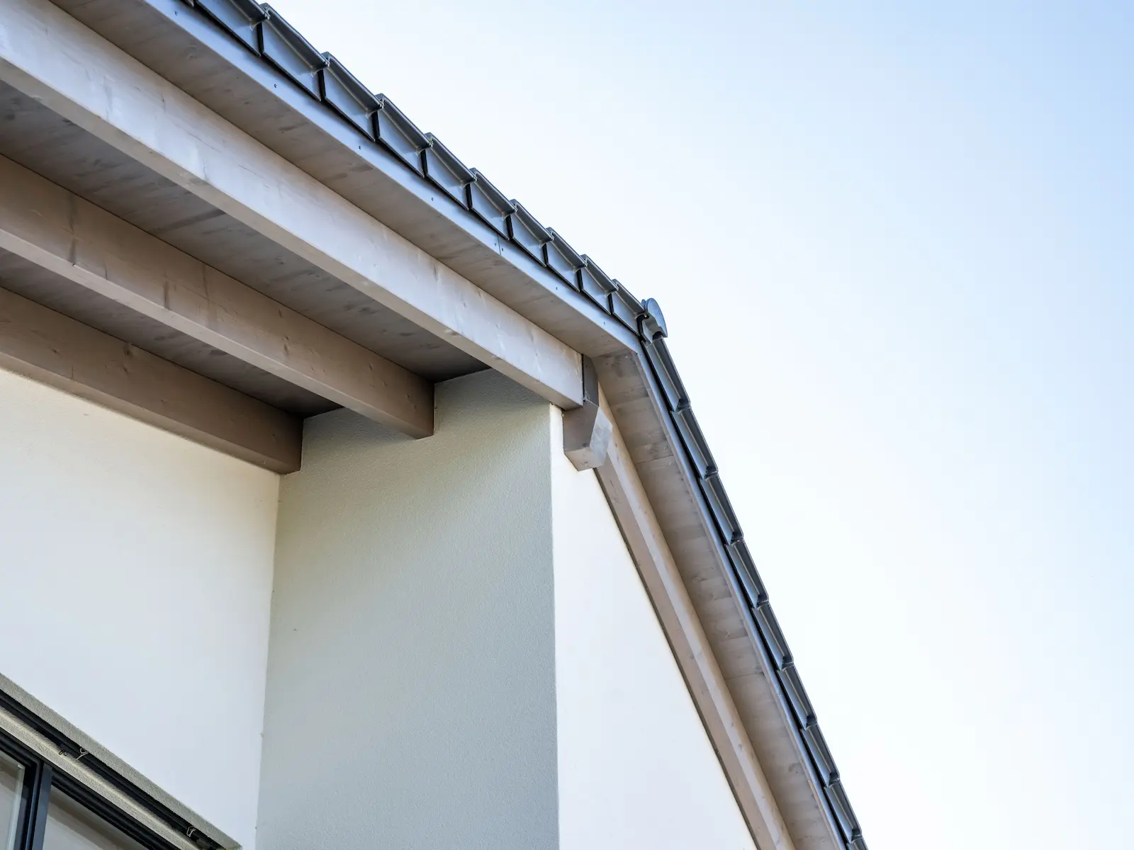 Aussenansicht des Einfamilienhauses mit weissem Verputz und sichtbarer Giebelseite aus Holzelementen