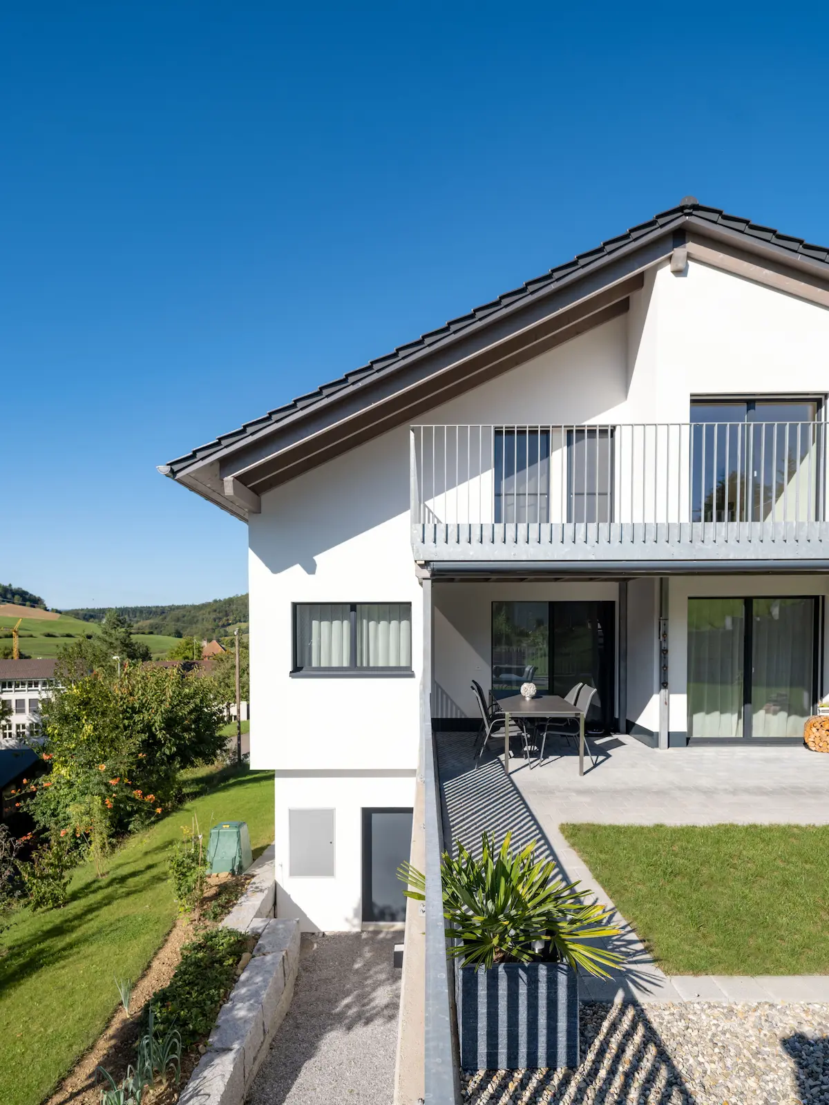 Rückseite des Hauses mit Balkon, Terrasse und grossen Fensterfronten