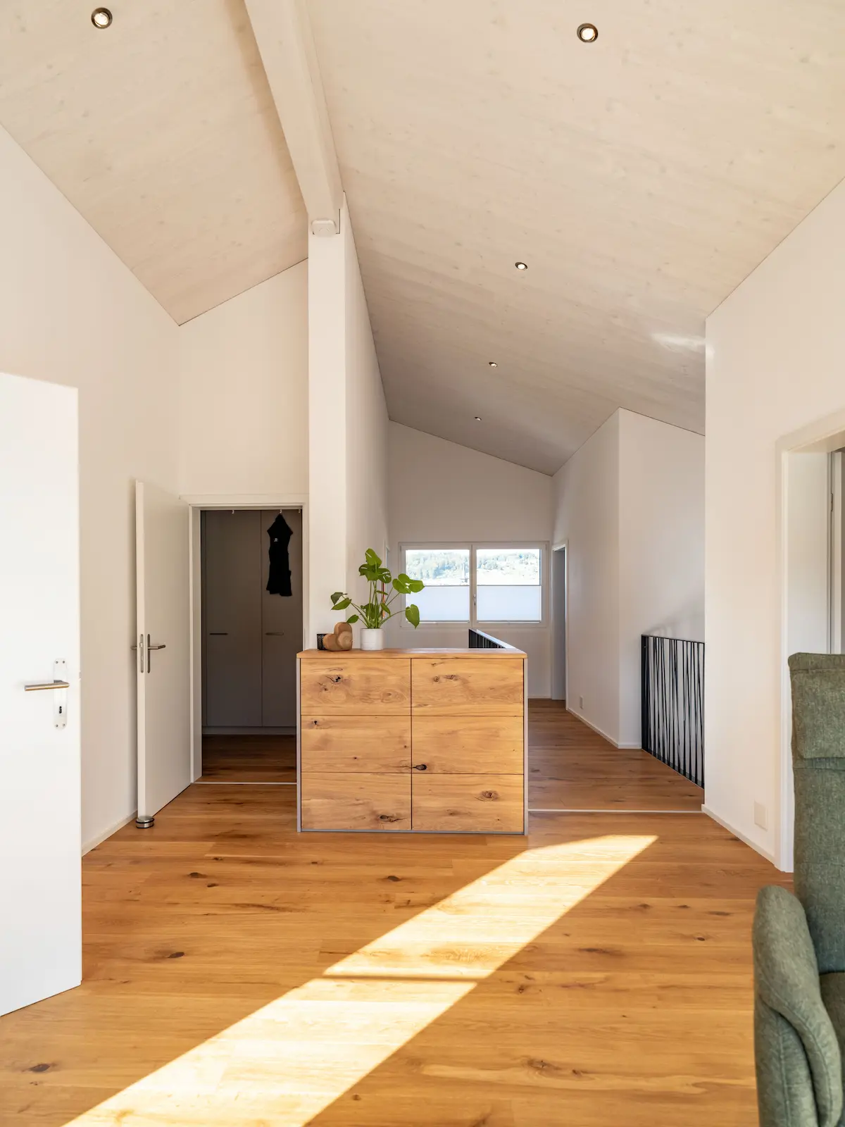Flur im Obergeschoss mit verputzten Holzelementwänden, Sideboard und Holzdecke