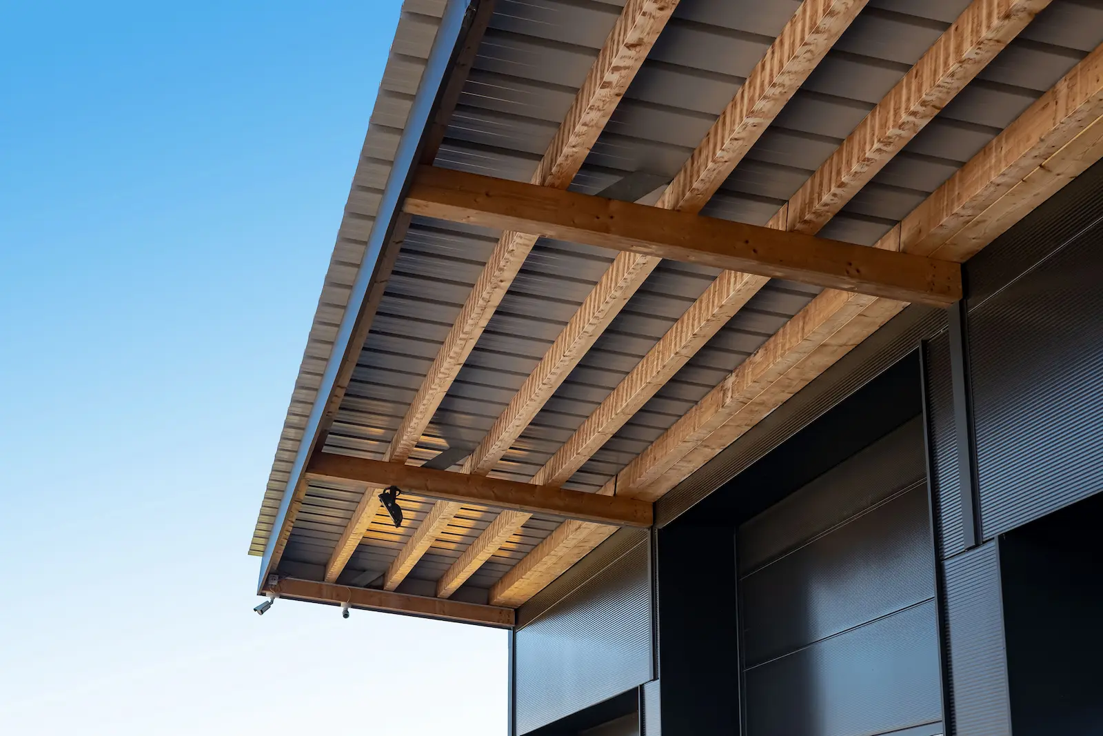 Aussenansicht Industriehalle mit Vordach in Holzbauweise und dunkler Fassadenverkleidung