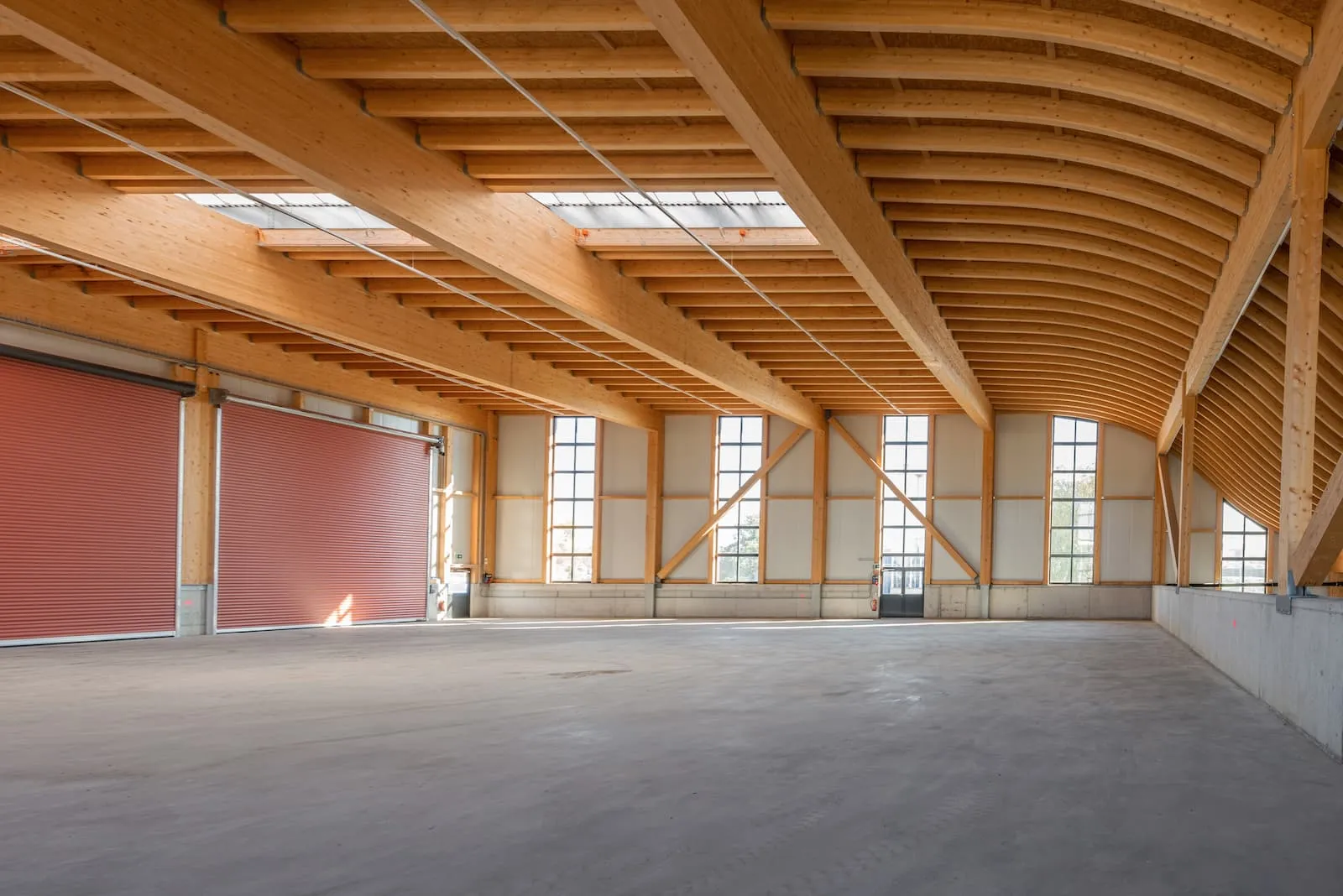 Leerstehender Halleninnenraum mit Holztragwerk und grossen Toren