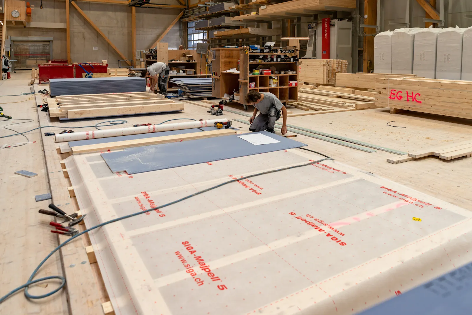 Vorfertigung von Holzelementen in der Werkhalle mit vorbereiteten Wandbauteilen