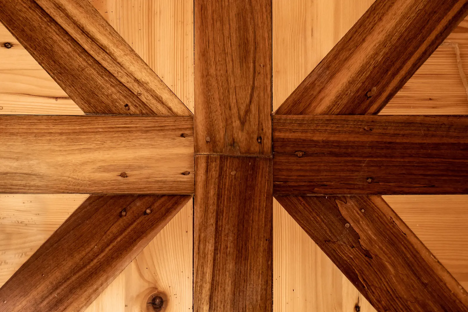 Detail saniertes Kreuzmotiv im historischen Riemenboden Kloster Fahr, dunkle Hölzer in heller Fläche