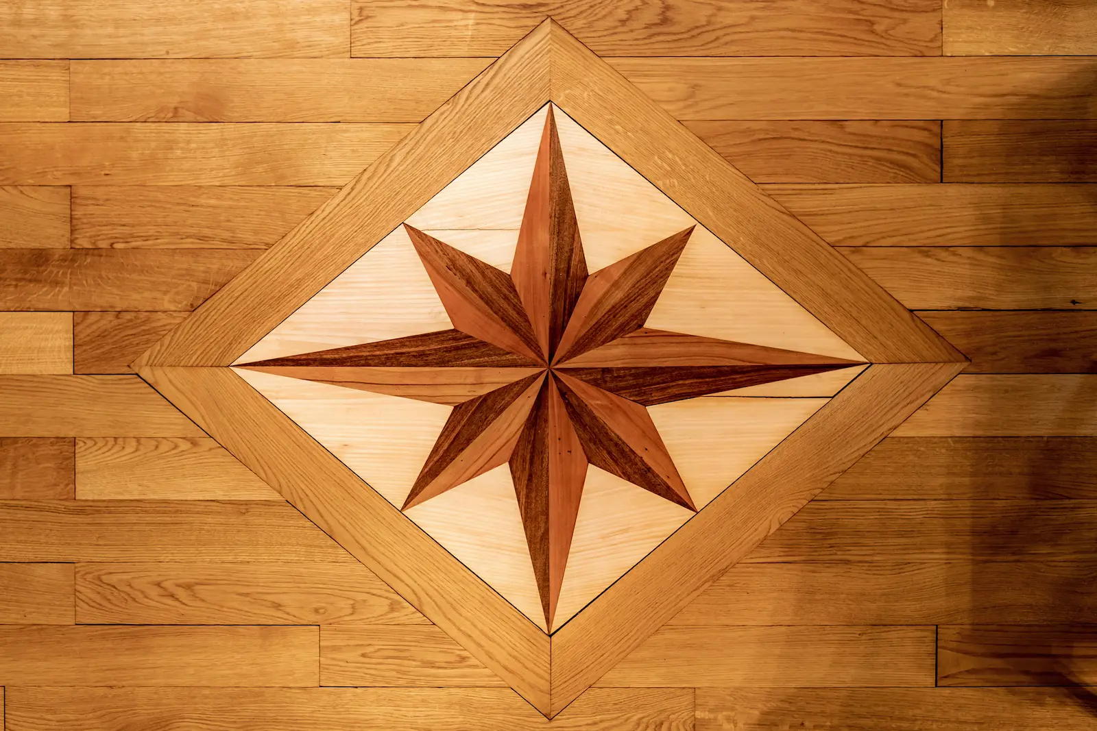 Detailaufnahme einer Intarsienarbeit im Riemenboden des Klosters Fahr, sternförmiges Muster in kontrastierendem Holz
