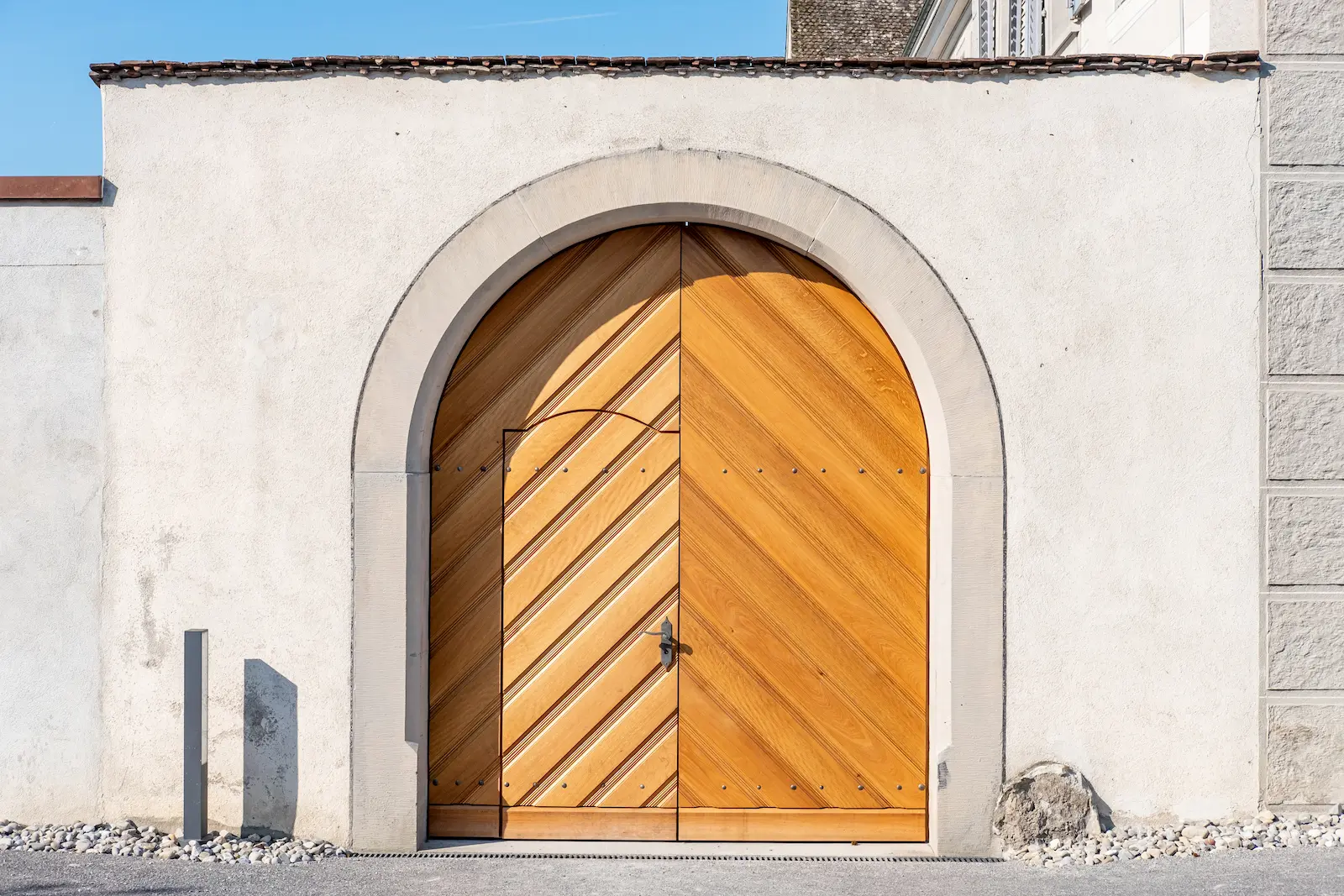 Restauriertes Holztor im Rundbogenportal des Klosters Fahr mit diagonaler Holzverschalung und Metallbeschlägen