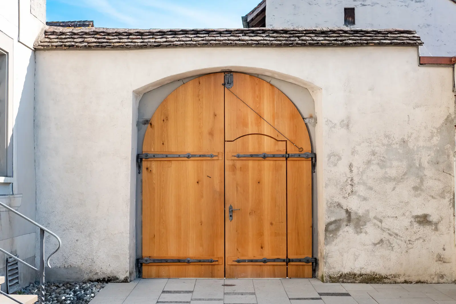 Sanierter Holztorbogen im Kloster Fahr, eingefasst von einer massiven Mauer, mit traditionellem Eisenbeschlag.