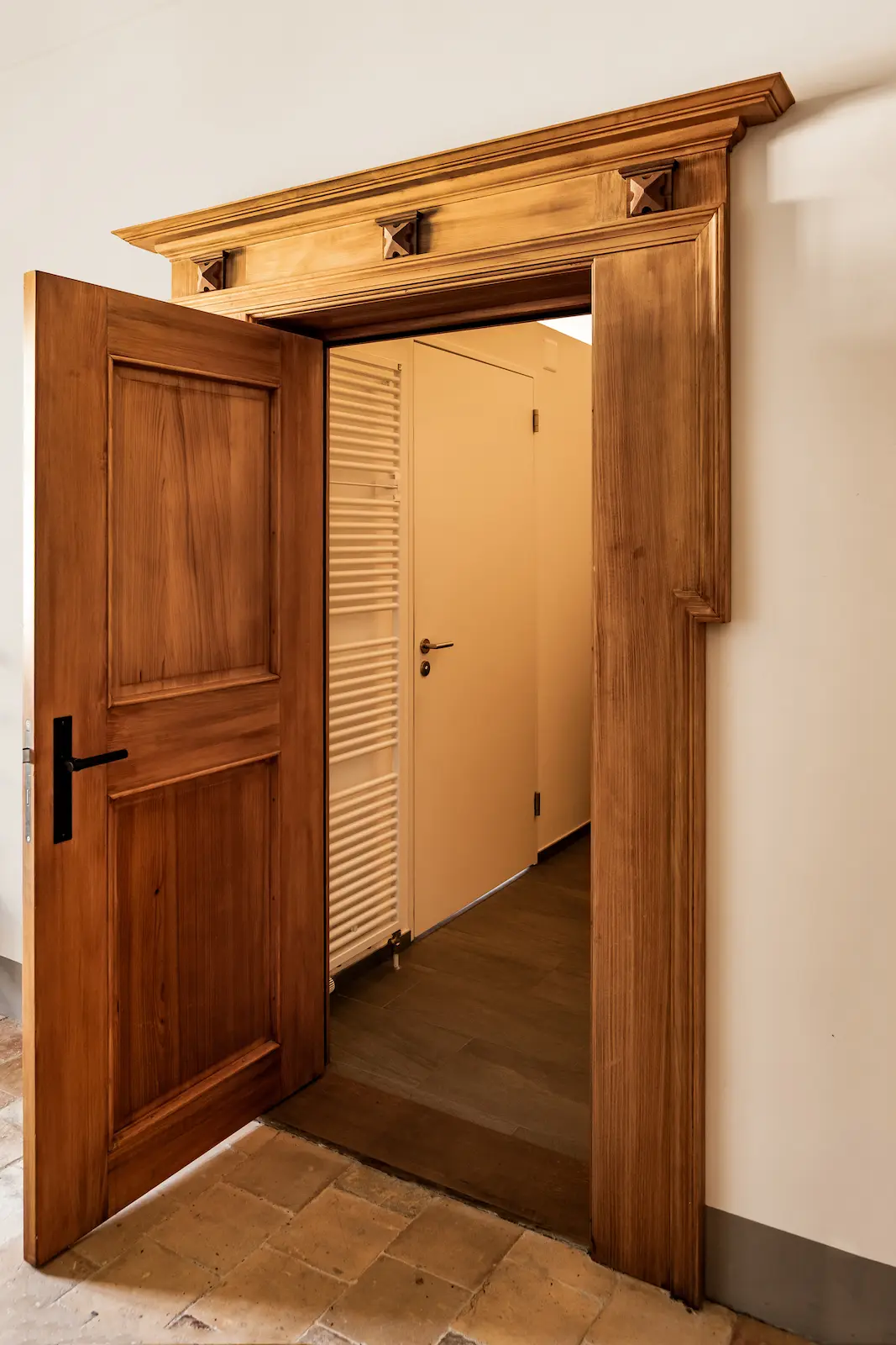 Geöffnete Holztüre im Kloster Fahr mit aufwendig gearbeitetem Türfries, die den Blick in einen modernen Raum freigibt.