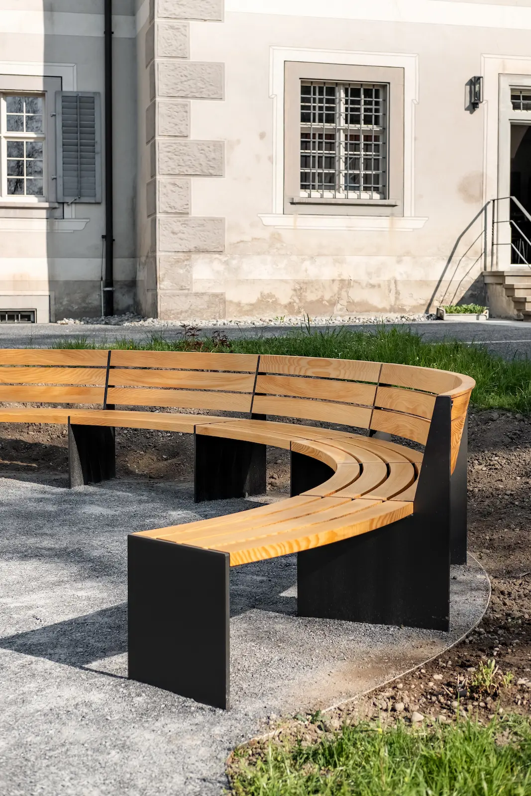 Gebogene Sitzbank aus Massivholz mit Stahlfüssen im Aussenbereich Kloster Fahr