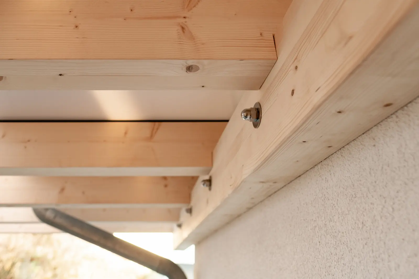 Anschluss des Holztragwerks an die Hausfassade mit sichtbaren Befestigungen.