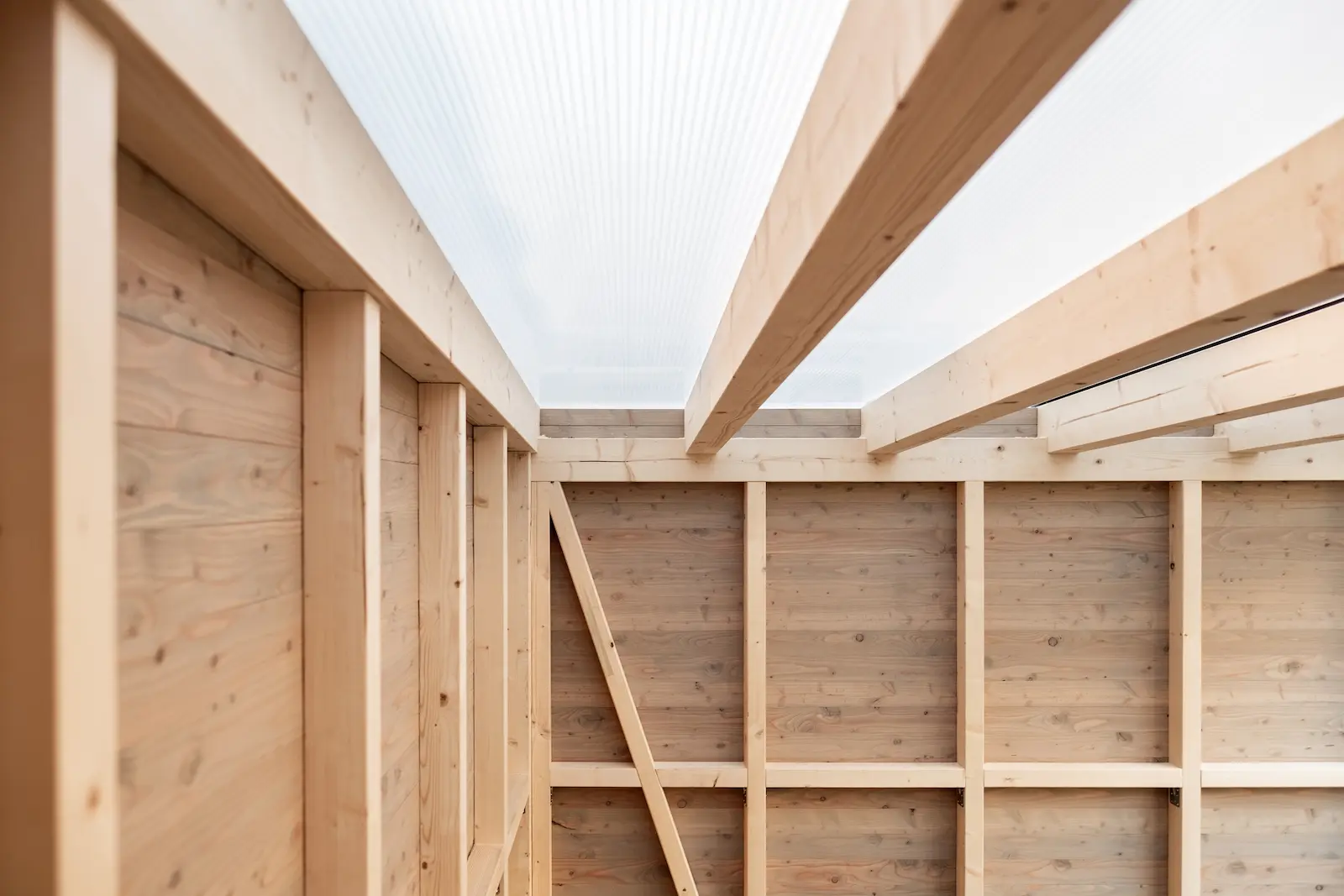 Dachkonstruktion des Unterstands mit Holzträgern und lichtdurchlässiger Abdeckung.