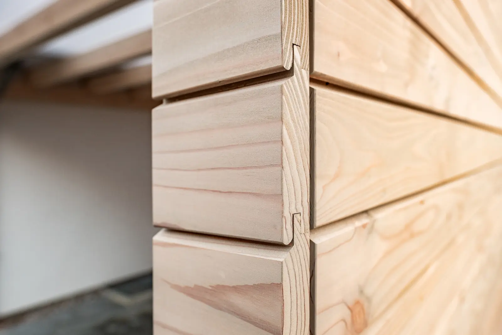 Detailaufnahme einer Holzecke mit Nut-und-Feder-Fassadenbrettern.