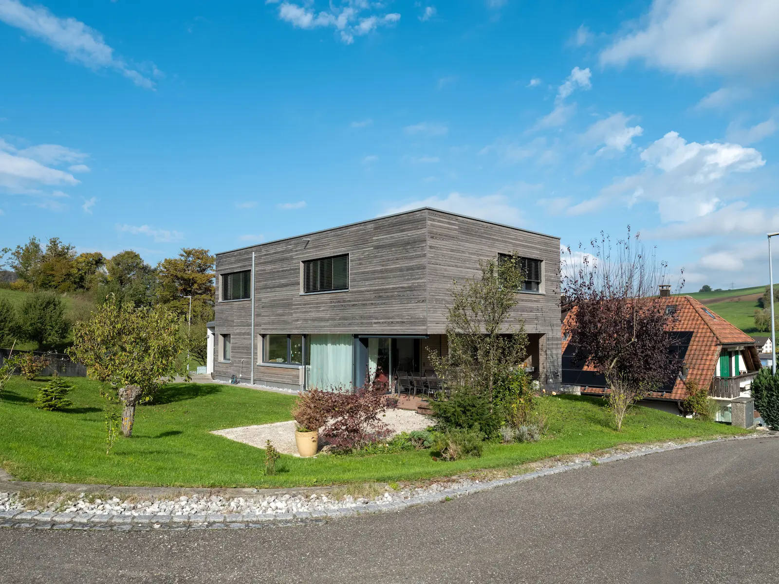 Strassenansicht Einfamilienhaus in Holzelementbau mit Garage, Flachdach und Holzfassade