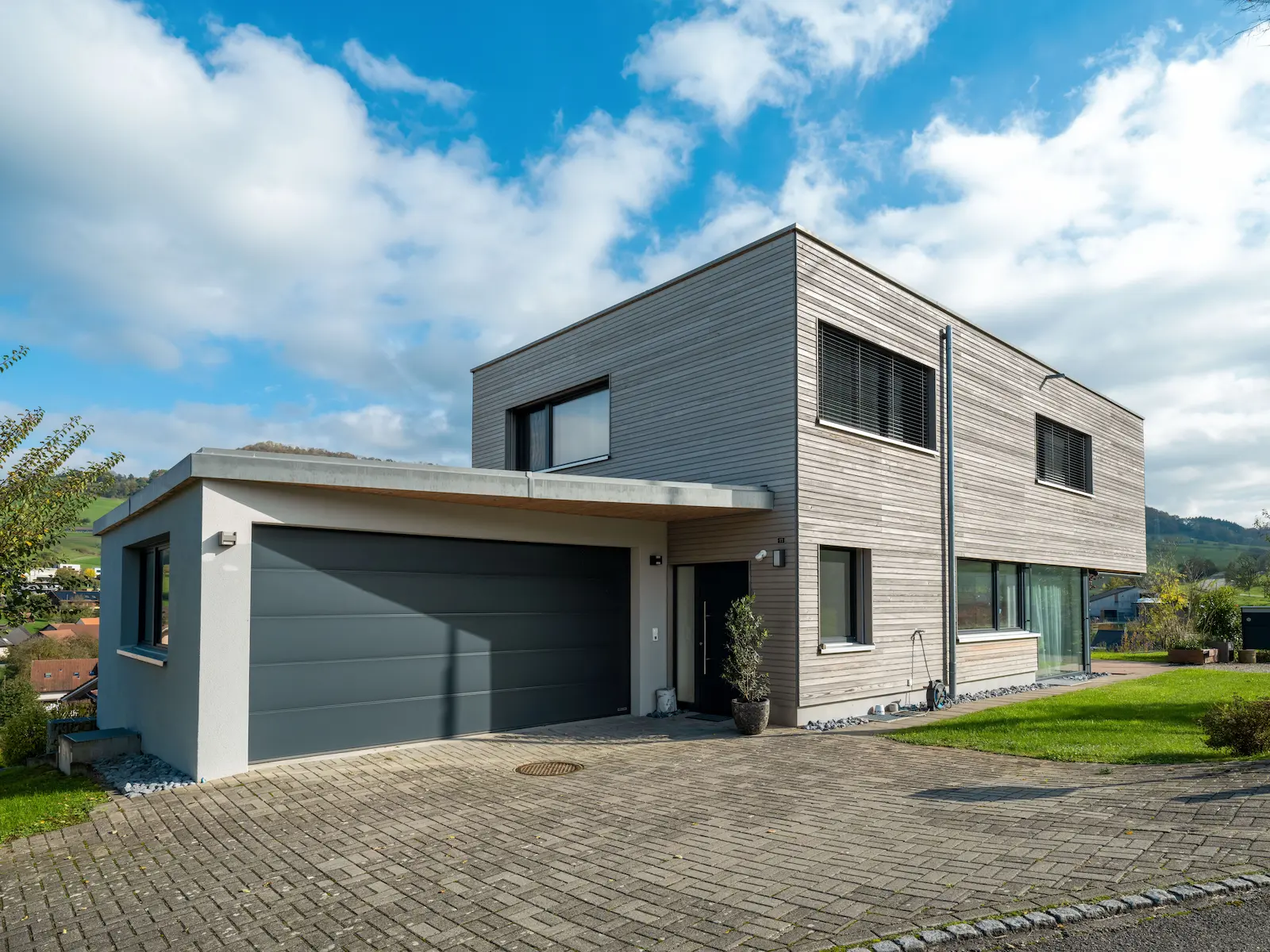 Rückseite des Einfamilienhauses mit gedecktem Sitzplatz und Holzfassade