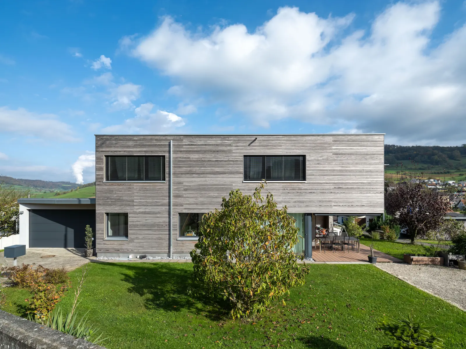Einfamilienhaus in Gansingen mit horizontaler, vorvergrauter Holzfassade und Flachdach