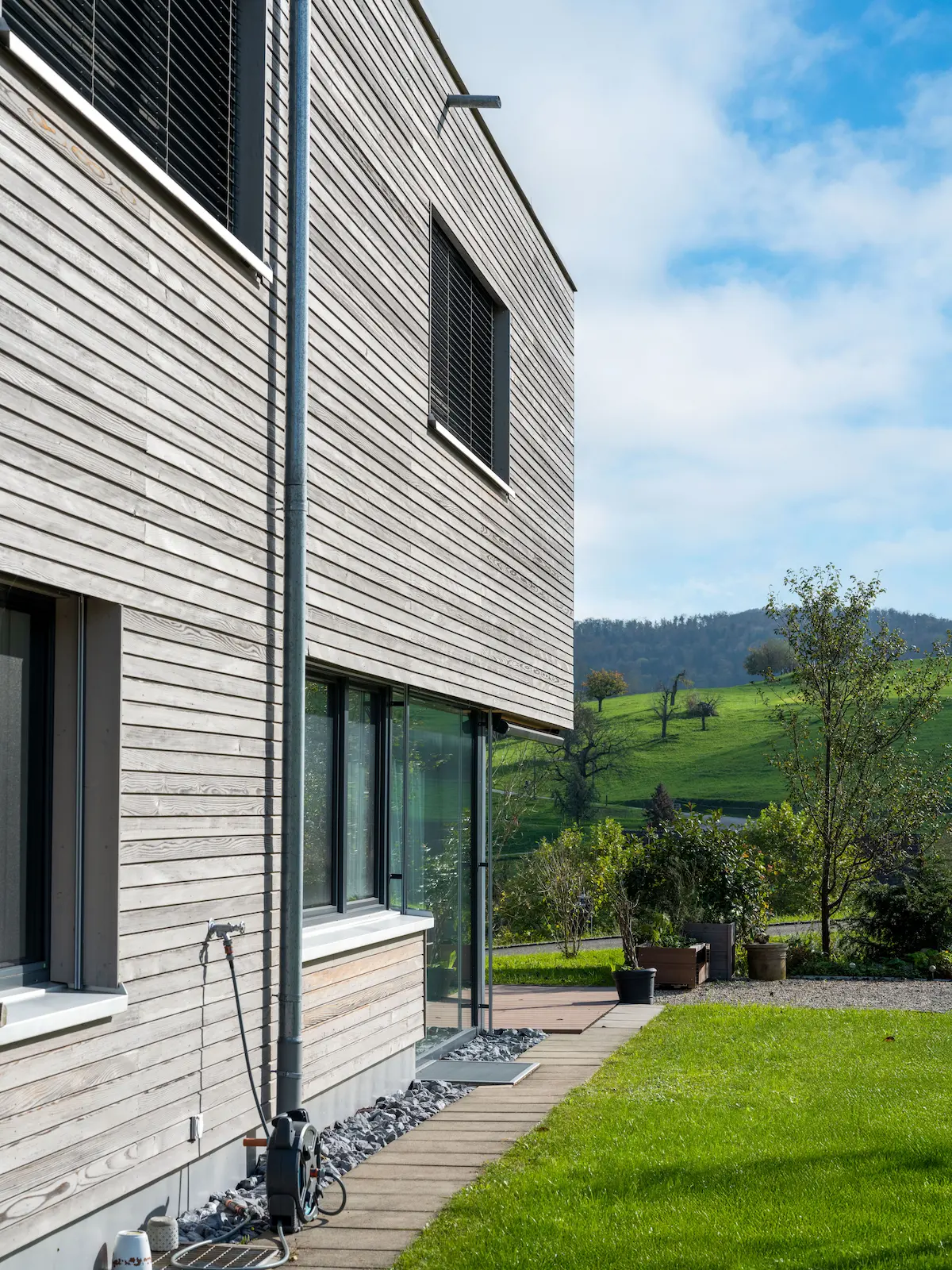 Detailansicht der horizontal montierten Holzfassade mit vorvergrauter Oberfläche und Fensterfront