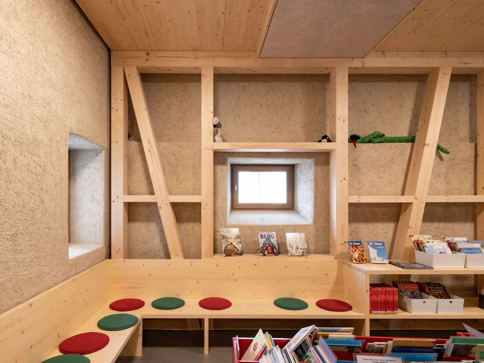 Bibliotheksraum mit sichtbarer Holzkonstruktion und Sitzbank