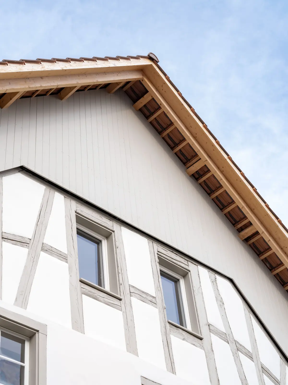 Giebelfassade mit Fachwerk und modernem Holzabschluss