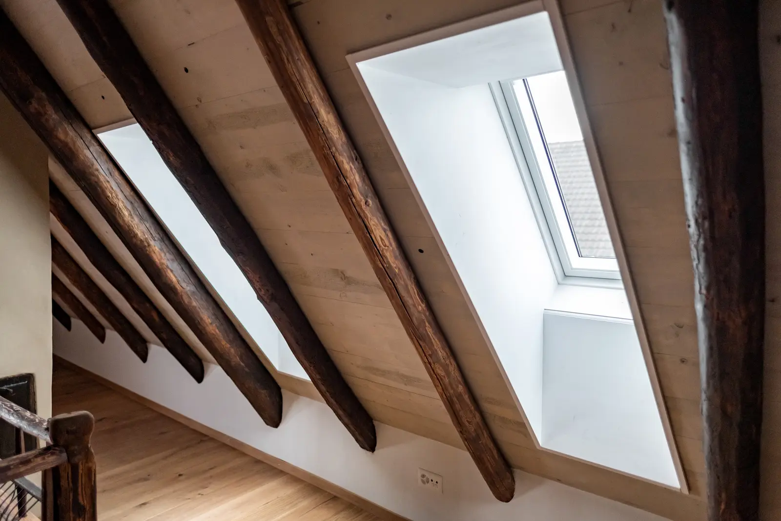 Schrägansicht zwei neu eingebauter Dachfenster zwischen historischen Sparren