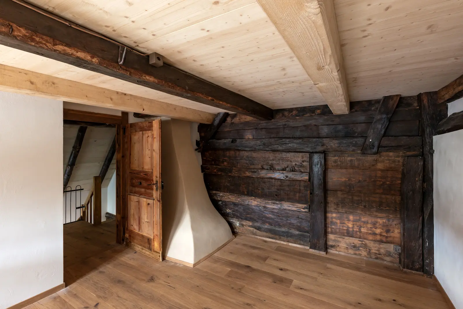 Obergeschoss mit sichtbarer Holzwand, restaurierten Balken und originaler Tür