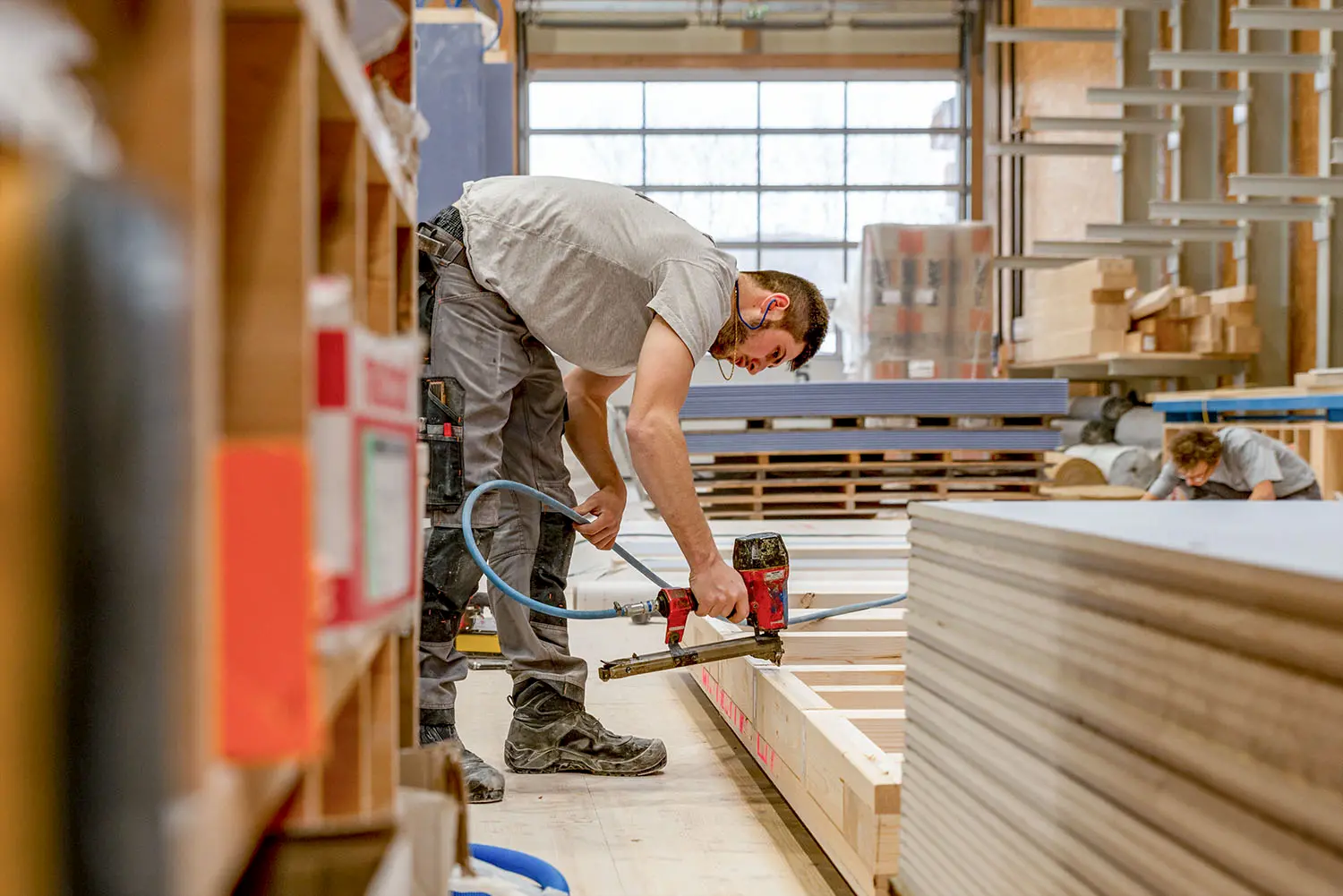 Ein Mitarbeiter der Vögeli Holzbau ist in der Werkhalle an der Vorfabrikation von Holzelementen beschäftigt