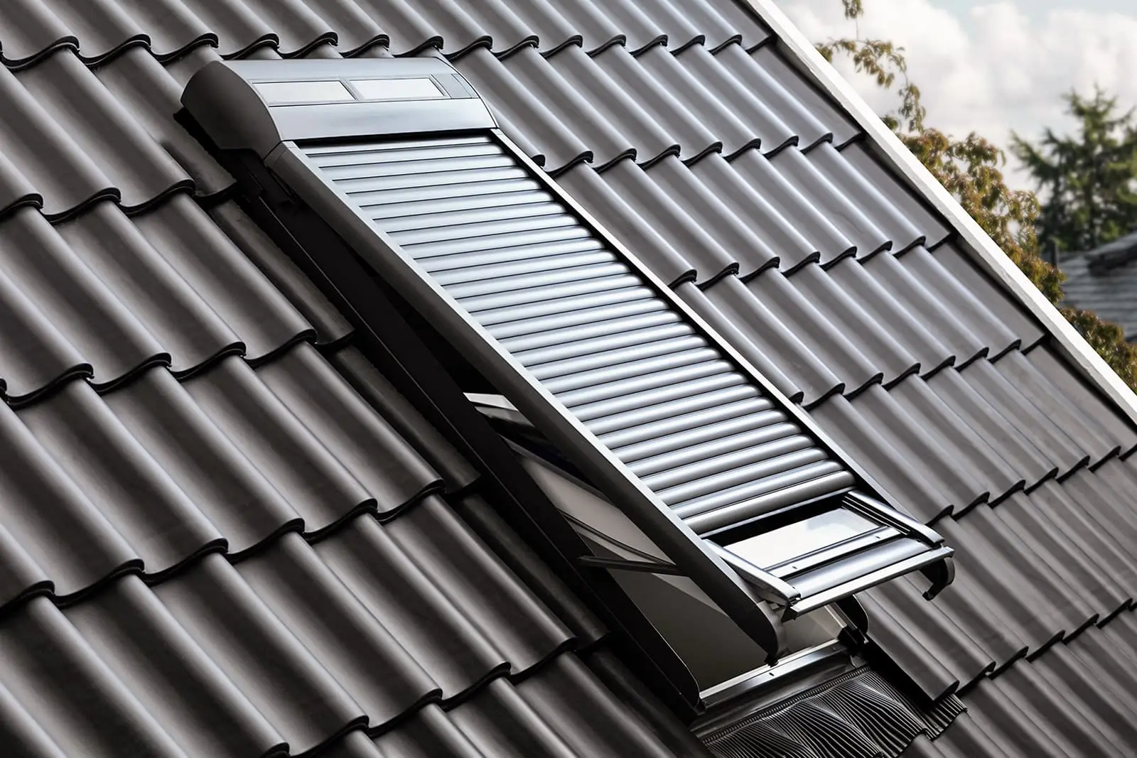 Dachfenster mit integriertem Rollladen auf frisch saniertem Dach mit dunklen Ziegeln.