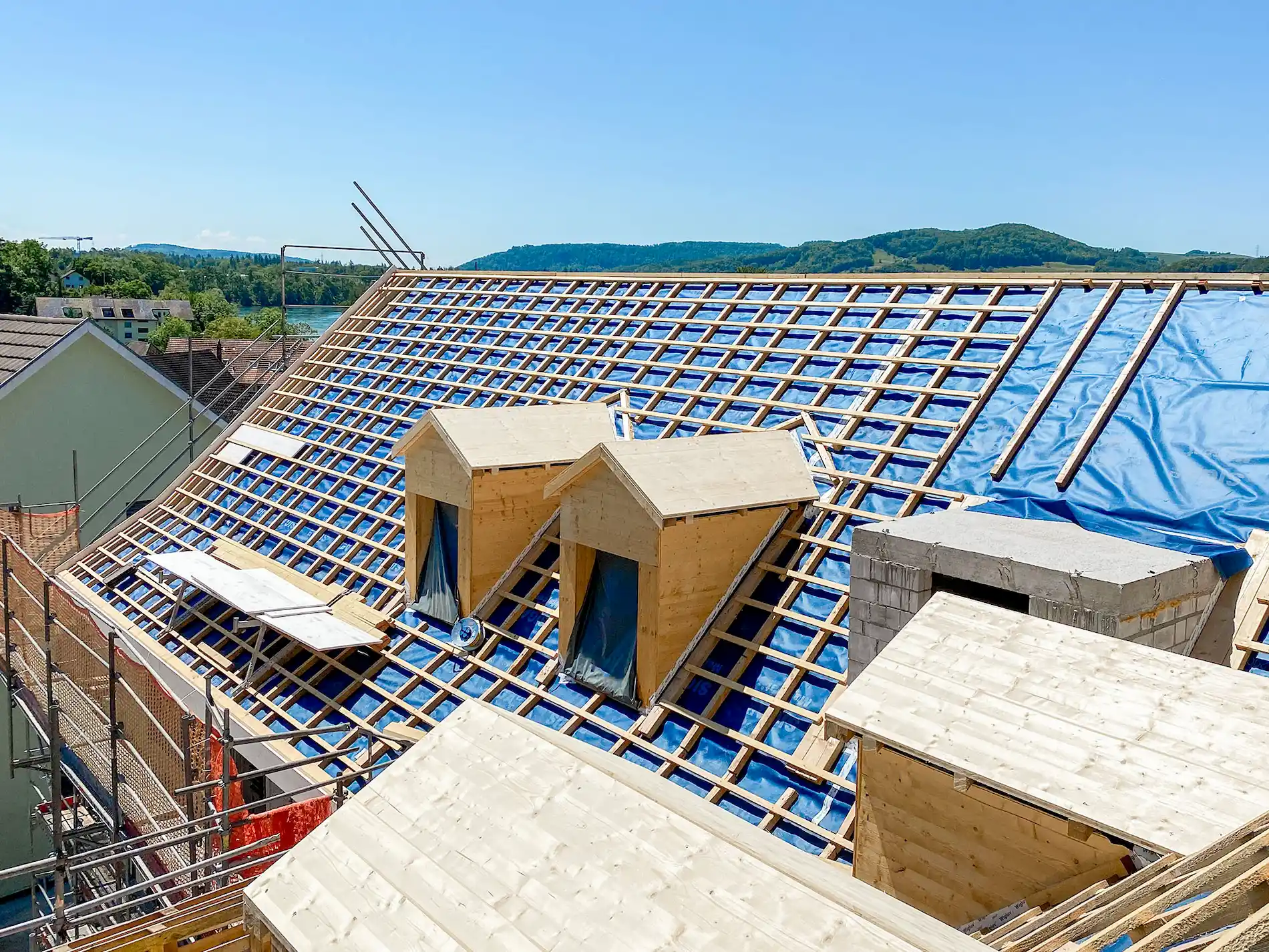 Dachsanierung mit neuen Gauben und vorbereiteten Dachfenstern, Holz- und Lattenkonstruktion auf einem Altbau mit Lukarnen.