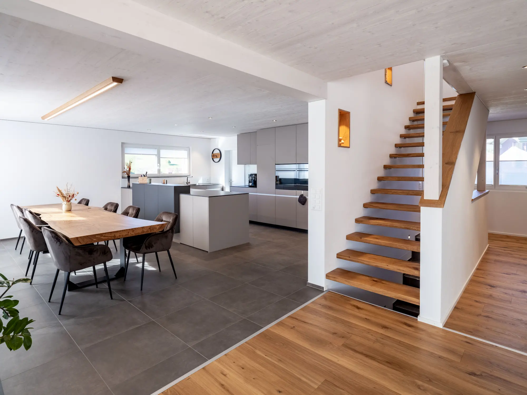 Wohnraum mit freitragender Treppe, Küche und verputzten Innenwänden