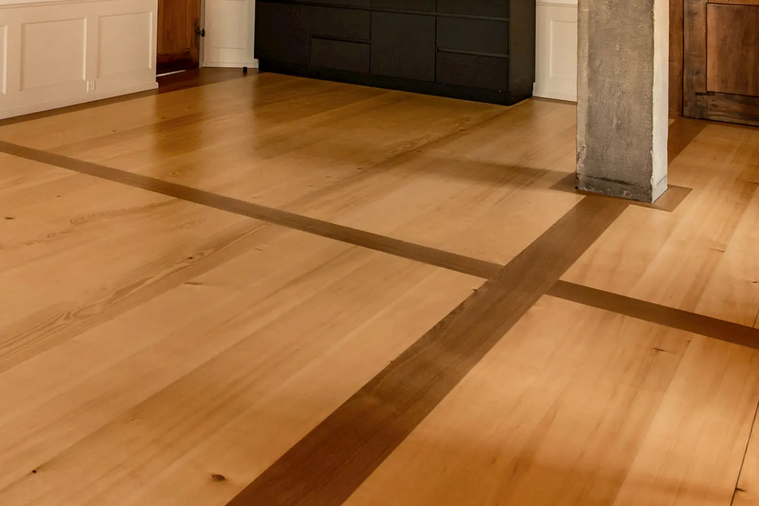 Hochwertiger Holzboden mit dunklen Intarsien – edle Handwerksarbeit und natürliche Materialien für stilvolle Innenräume.