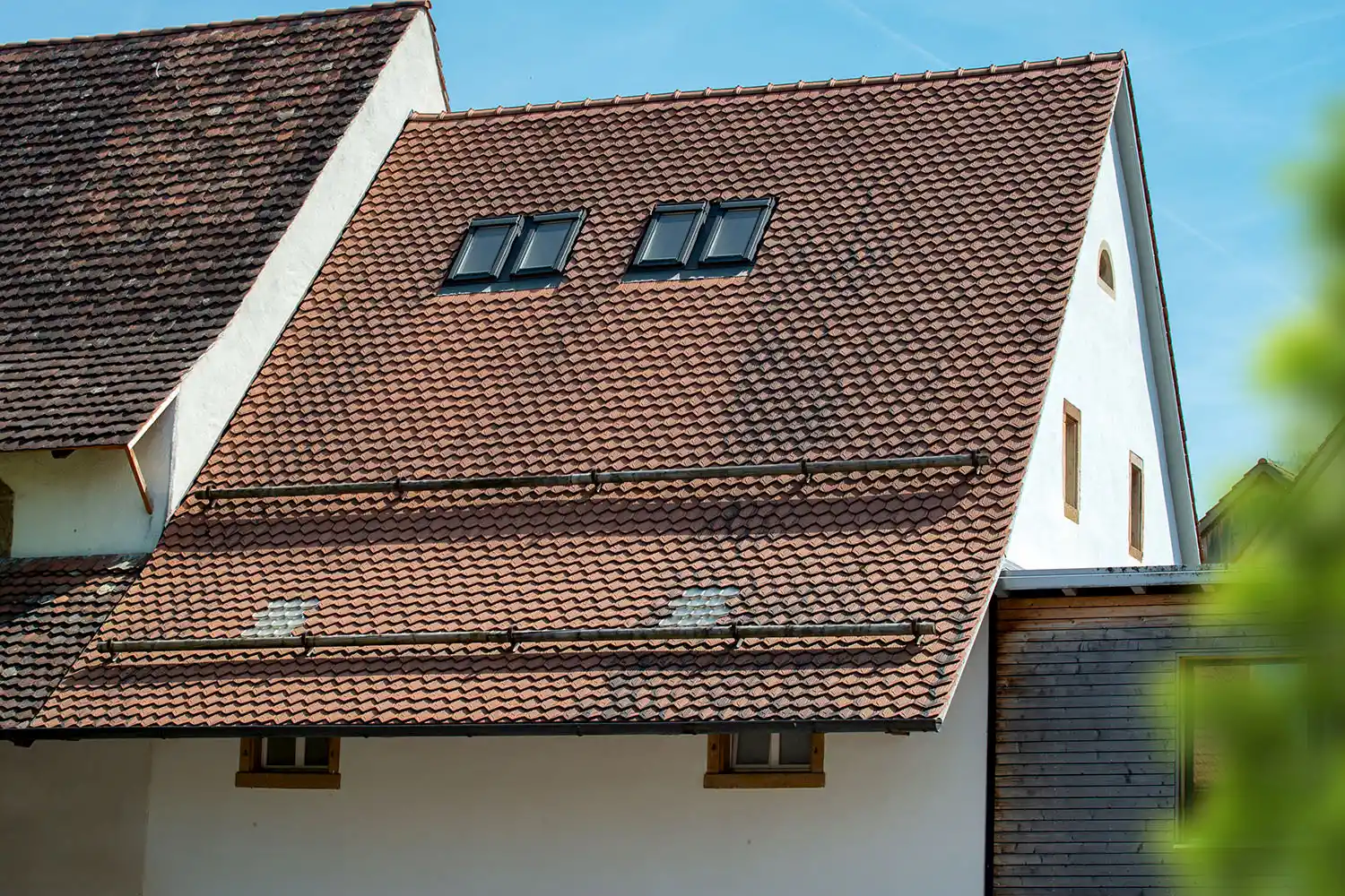 Traditionelle Dachsanierung mit roten Ziegeln und Holzdetails – sorgfältige Restaurierung historischer Gebäude.