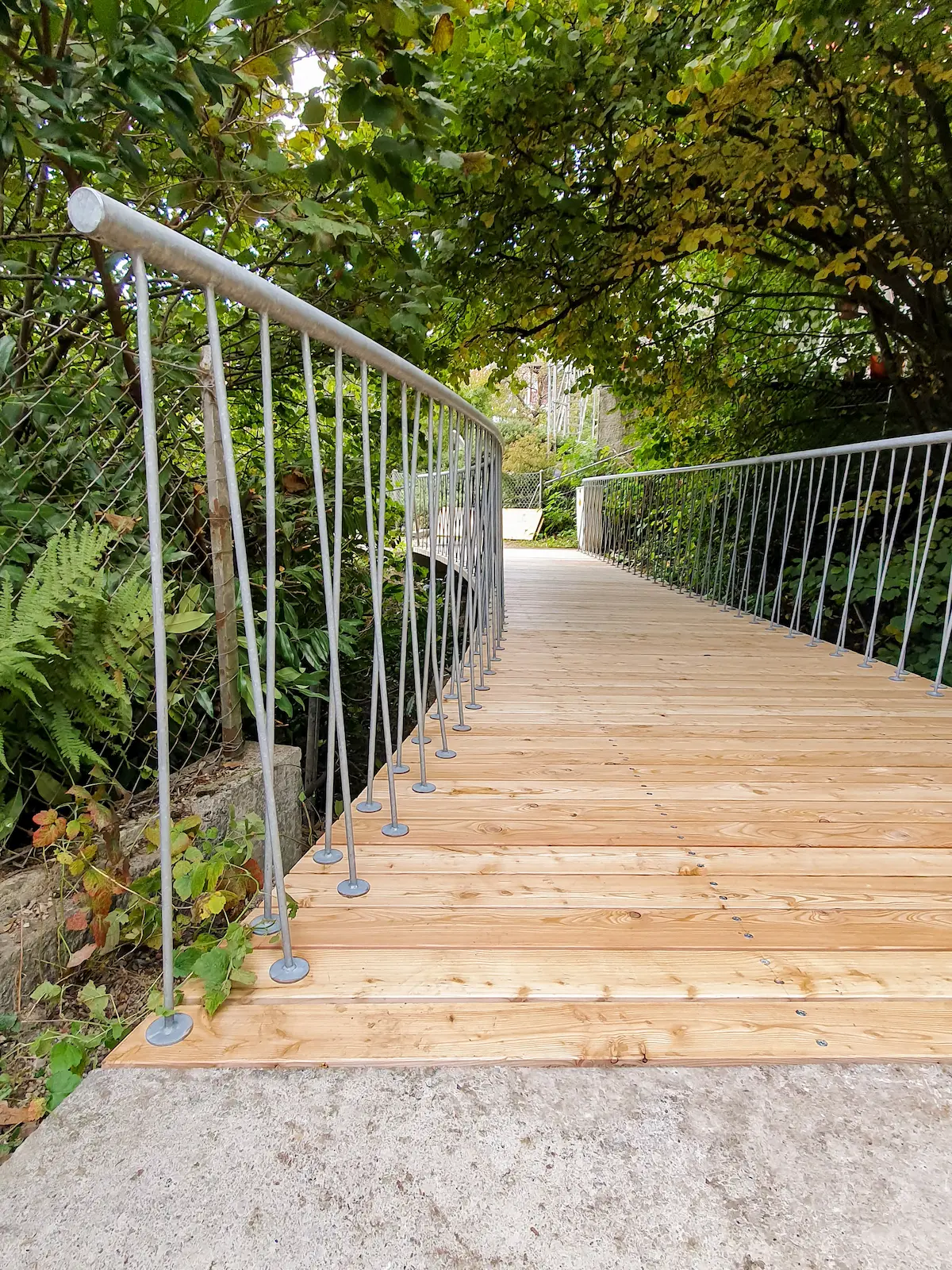 Holzbrücke mit neuem Belag und Metallgeländer im Grünen, Ennetbaden